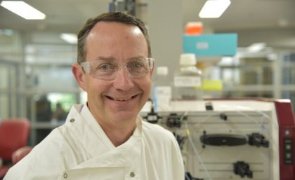 Portrait photo of UQ Professor Trent Munro wearing a white coat in a laboratory. Supplied.